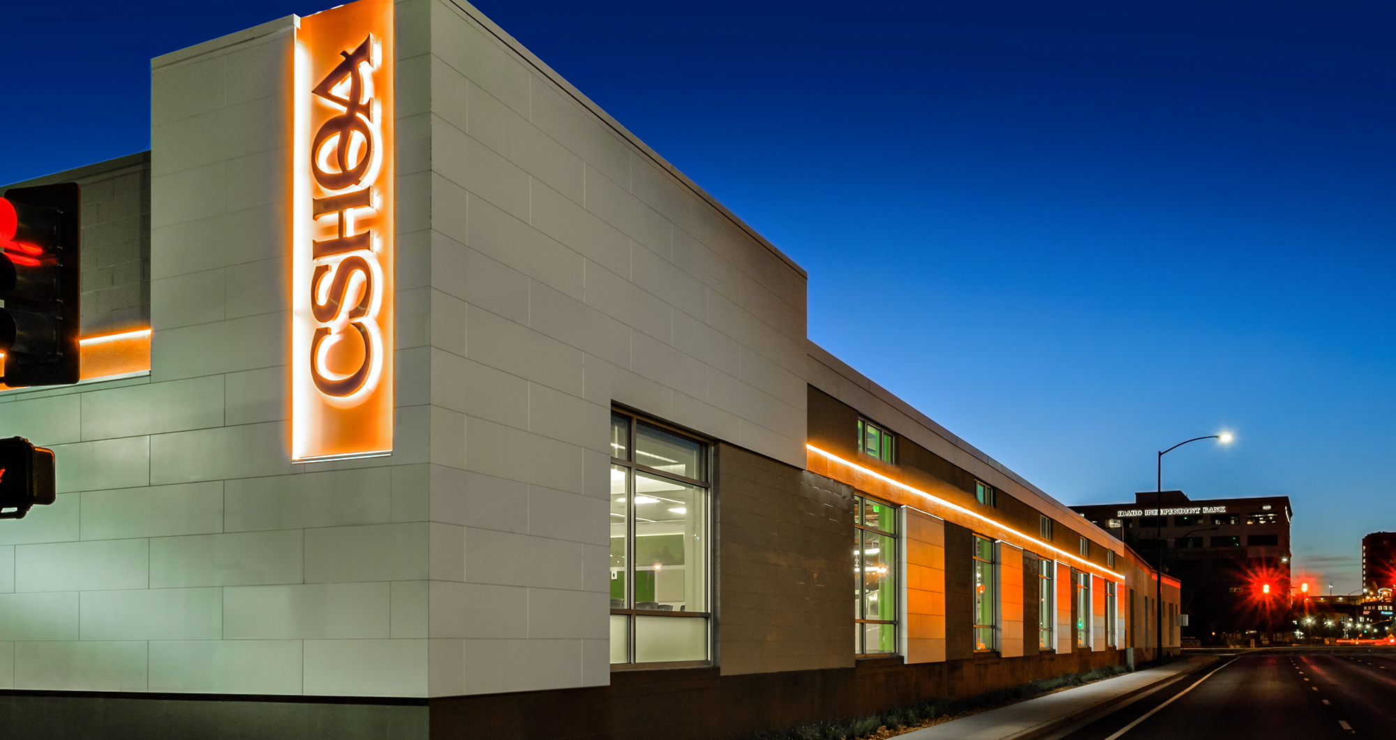 CSHQA’s Boise office at dusk, with the illuminated vertical CSHQA sign and orange accent lighting along Broad Street.