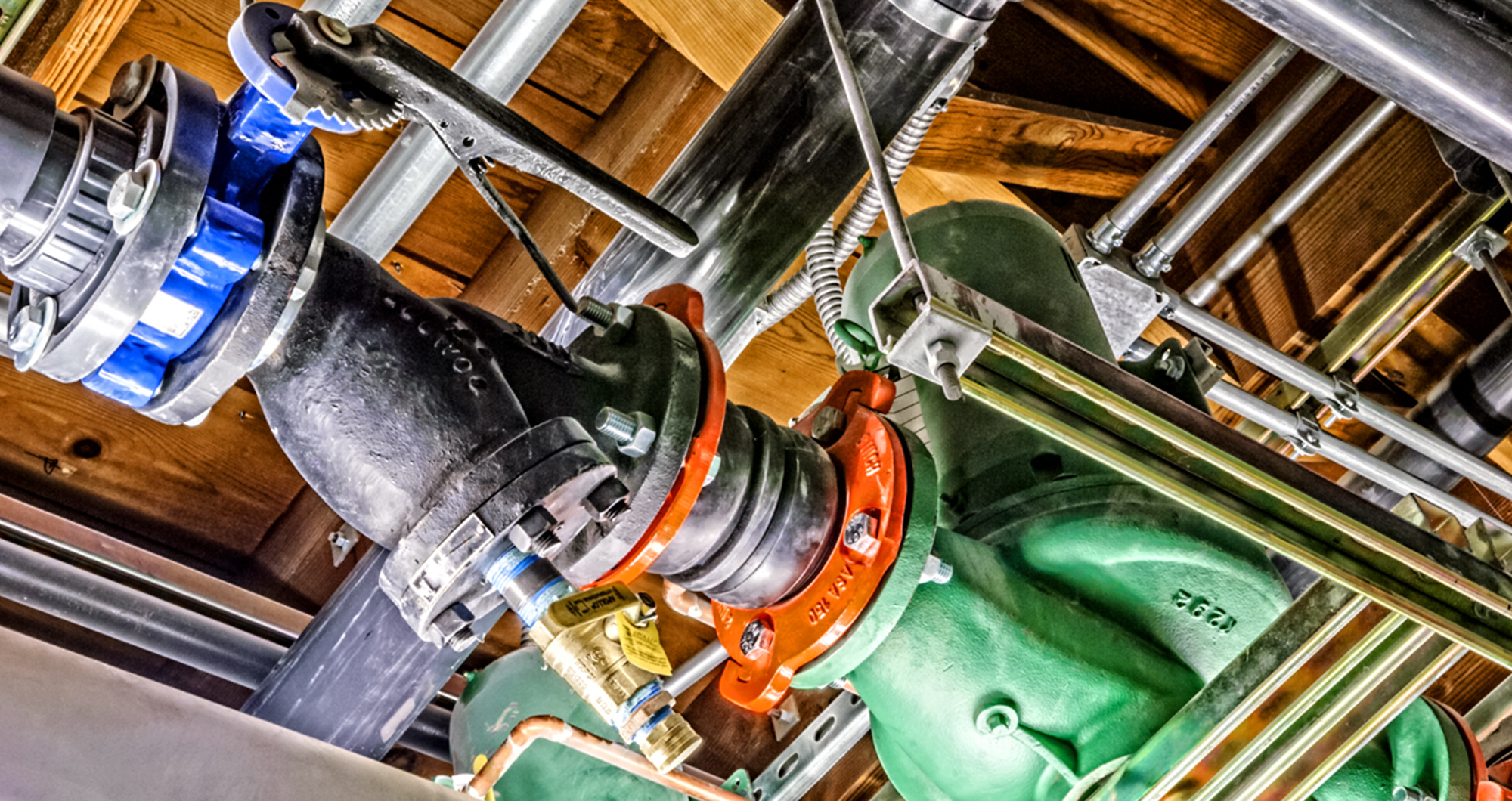 Heat pump piping and circulation pumps beneath the original wood roof framing at CSHQA’s Boise office.
