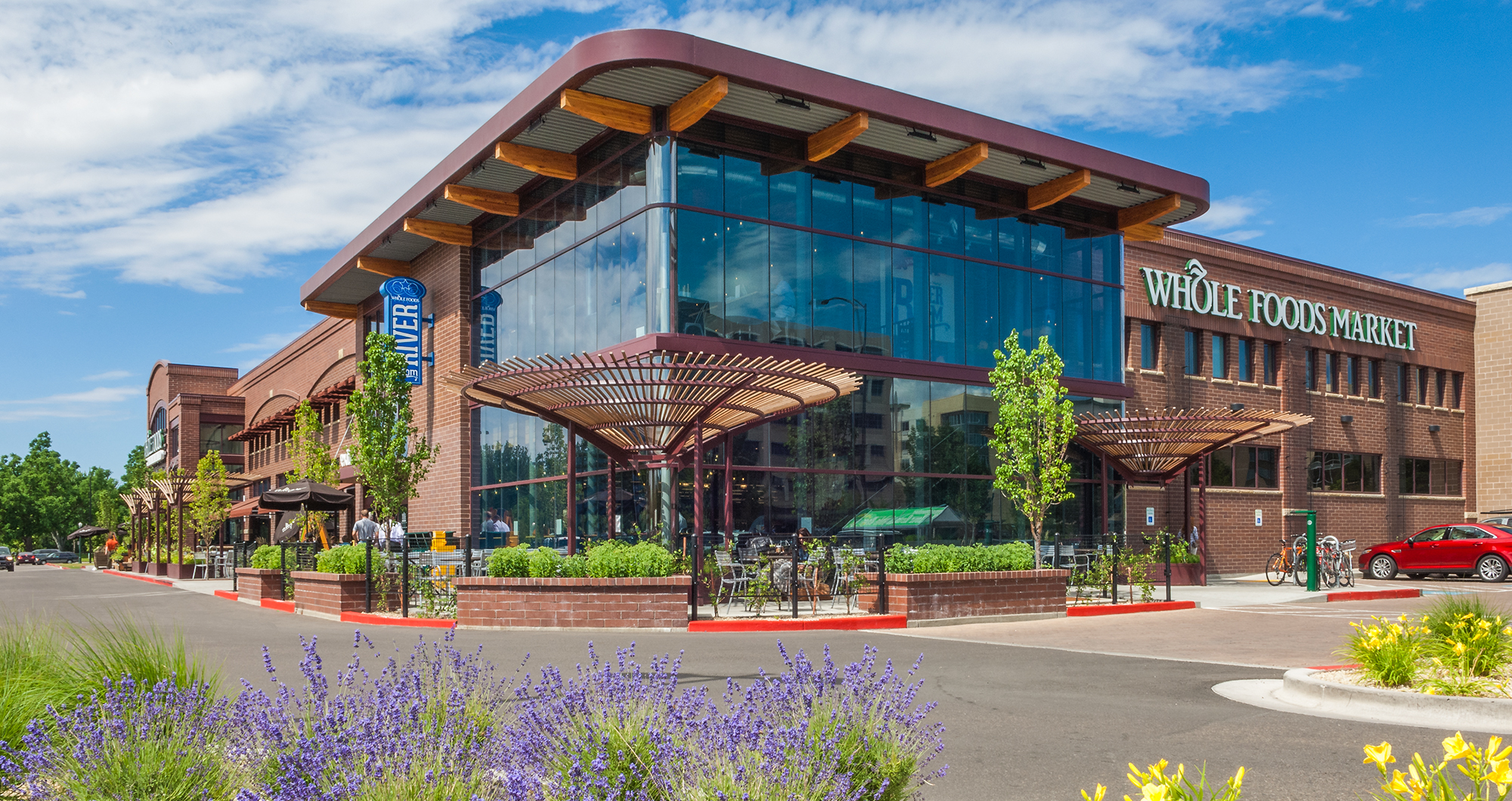 Boise’s Whole Foods Market at River Park Place, with the glass River Room corner, steel and wood trellises, and lavender along Broadway.